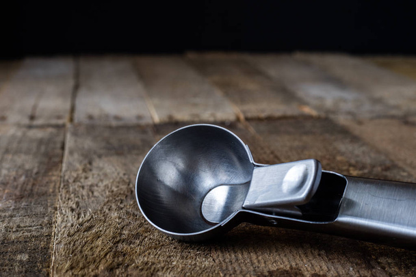 Metal kitchen utensils on a wooden kitchen table. Dark background. - 写真・画像