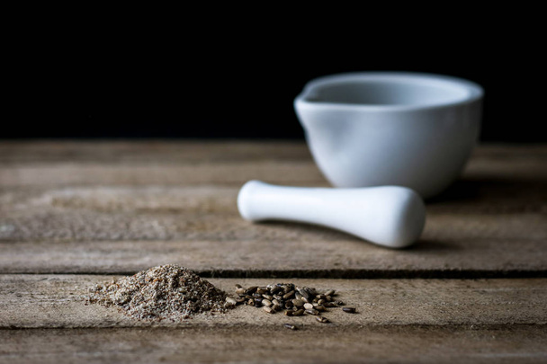 Mortar and milk thistle on a wooden kitchen table. - Foto, afbeelding