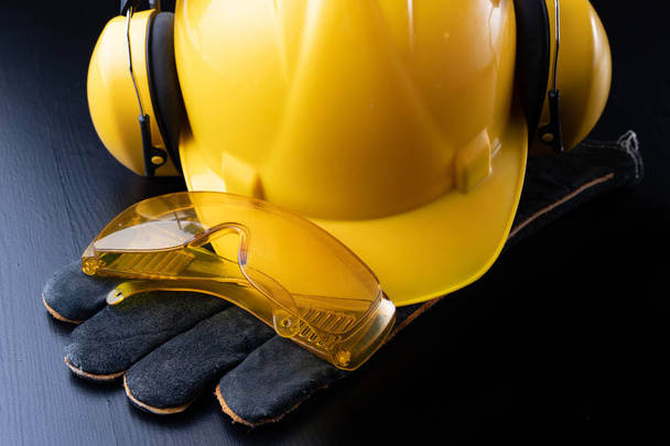 Helmet and accessories for construction workers. Accessories needed for work on the construction site. Dark background. - Photo, Image
