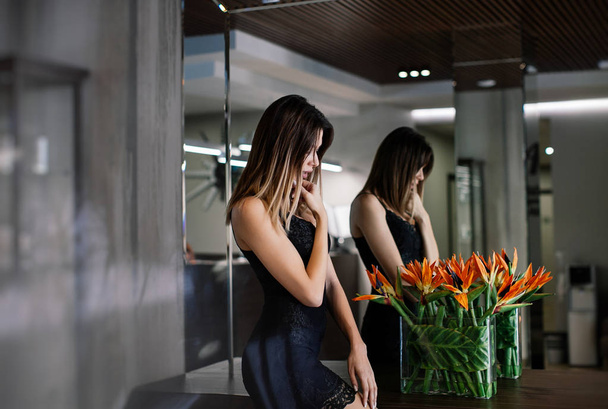 szexi lány fekete ruhában pózol a tükör egy drága szállodában - Fotó, kép