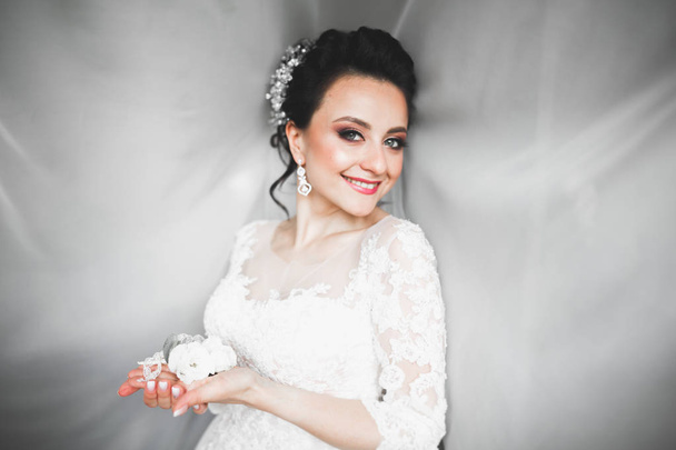 Beautiful bride wearing fashion wedding dress with feathers with luxury delight make-up and hairstyle, studio indoor photo shoot - Foto, imagen