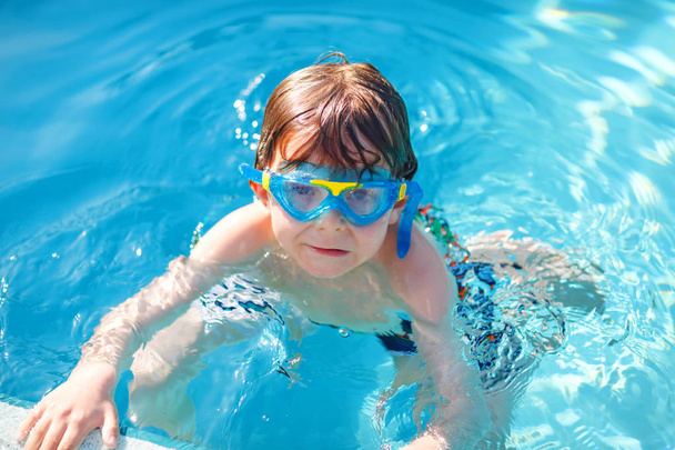 little preschool kid boy making swim competition sport. Kid with swimming goggles reaching edge of the pool . Child having fun in an swimming pool. Active happy child winning. sports, active leisure. - Zdjęcie, obraz