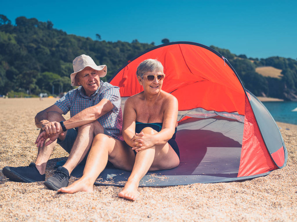 A senior couple is relaxing in a beach shelter - 写真・画像