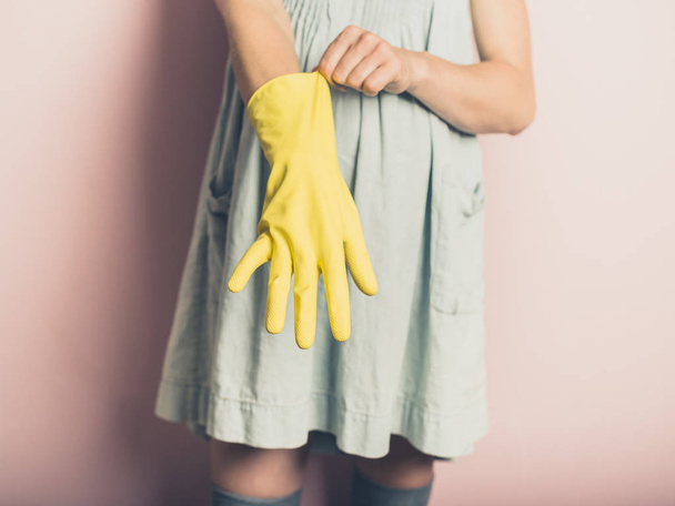 A young woman is putting on a rubber glove - Foto, afbeelding