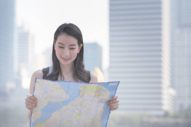 Bella asiatica donna turistica solo guardando la mappa alla ricerca di turisti visite spot. Viaggi in vacanza in estate
. - Foto, immagini