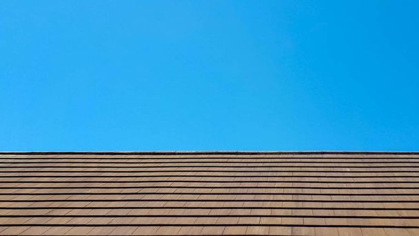 Une vue de face uniquement d'un beau toit brun dans le tiers inférieur de la photo, avec un ciel propre et assez bleu en arrière-plan
 - Photo, image