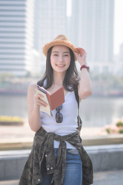 Hermosa mujer turista asiática sola sonriendo y buscando turistas punto de interés turístico. Viajes de vacaciones en verano
 - Foto, Imagen