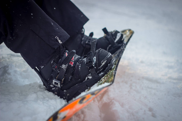 karda oturup snowboard. yakın çekim tahtaları ve ayakkabı. - Fotoğraf, Görsel
