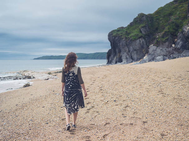 A young woman is walking on the beach - 写真・画像