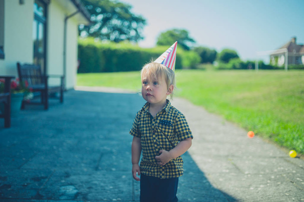 A cute little toddler has got his party hat on in the summer - Zdjęcie, obraz