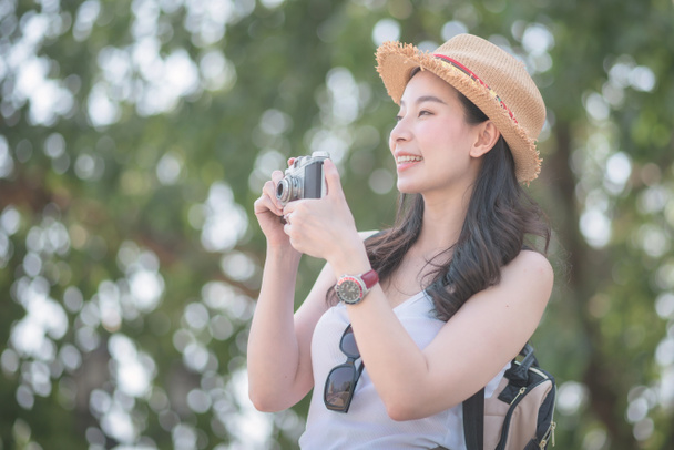 Hermosa mujer turista asiática en solitario disfrutar de tomar fotos por la cámara retro en el punto turístico. Viajes de vacaciones en verano
.  - Foto, Imagen