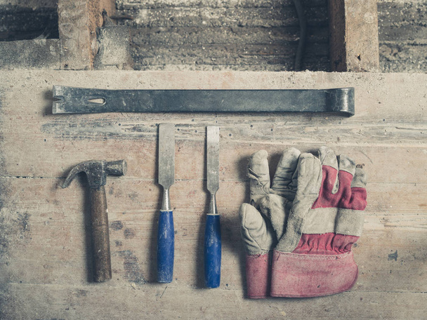 A pair of workman gloves a crowbar two chisels and a hammer on a wooden floor - Foto, immagini
