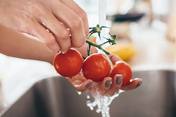 Mujer lavando tomates en fregadero de cocina de cerca
. - Foto, imagen