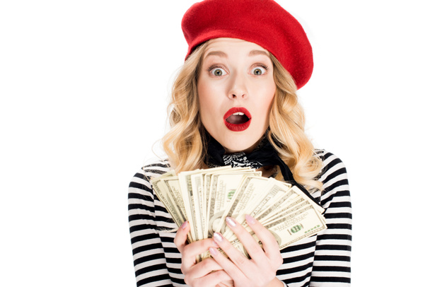 verbaasd blonde vrouw bedrijf dollar biljetten in handen geïsoleerd op wit  - Foto, afbeelding