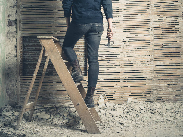A young woman is standing on a stepladder by an old wattle and daub wall - Foto, Bild