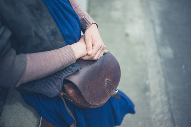 A young woman with a handbag outside in the city - Foto, imagen