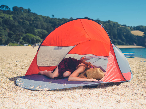 Een jonge vrouw is slapen in een schuilplaats strand in de zomer - Foto, afbeelding