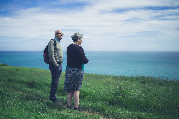 Una pareja de ancianos está junto al mar en un acantilado admirando el paisaje
 - Foto, imagen