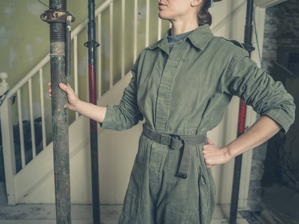 Στέκεται με κάποια στηρίγματα ακροβατικά σε ένα σπίτι για μια νεαρή γυναίκα που φοράει ένα κοστούμι boilr - Φωτογραφία, εικόνα