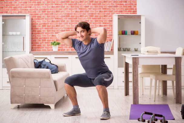 Joven hombre guapo haciendo ejercicios deportivos en casa
  - Foto, imagen