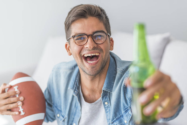 Portrait of man with beer and rugby ball at home - Foto, immagini
