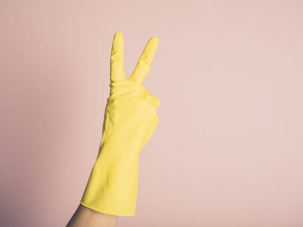 A female hand wearing a yellow rubber glove is displaying a rude gesture - Fotoğraf, Görsel