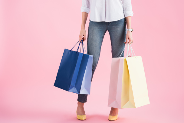 vista recortada de la niña sosteniendo bolsas de compras, aislado en rosa
 - Foto, Imagen