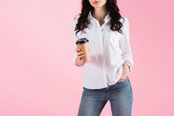 cropped view of woman holding disposable cup of coffee, isolated on pink - Fotó, kép