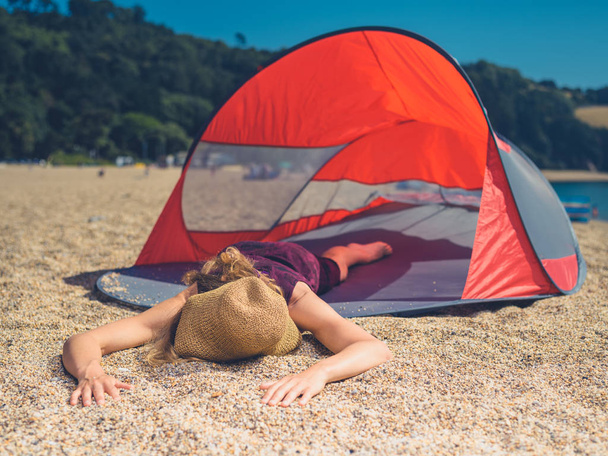 A young woman is sleeping in a beach shelter in the summer - Foto, imagen