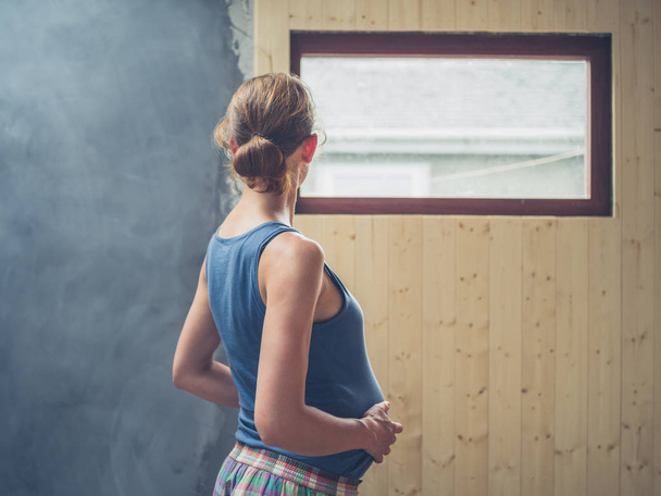 A young pregnant woman is standing by the window - Photo, image
