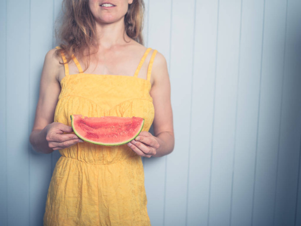 A young woman in a yellow dress is eating water melon - Photo, image