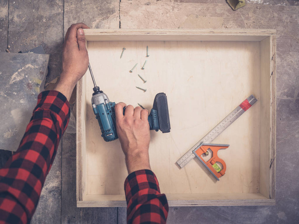 A carpenter is building a drawer in his workshop - Foto, Bild