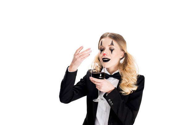 payaso femenino en traje oliendo vino mientras sostiene el vidrio aislado en blanco
  - Foto, Imagen