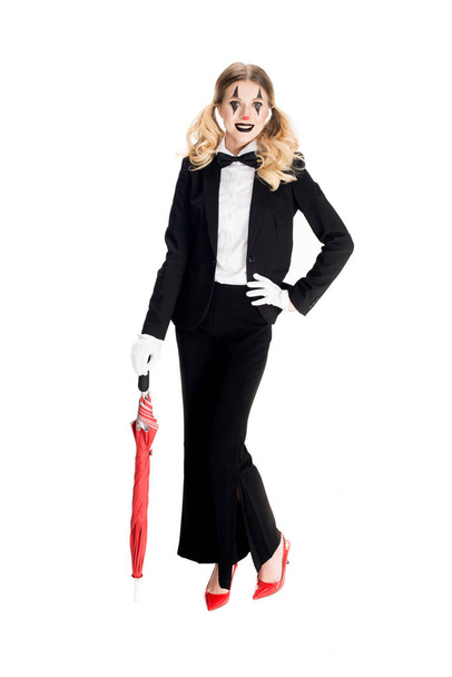 happy female clown holding umbrella while standing in suit isolated on white  - Fotoğraf, Görsel