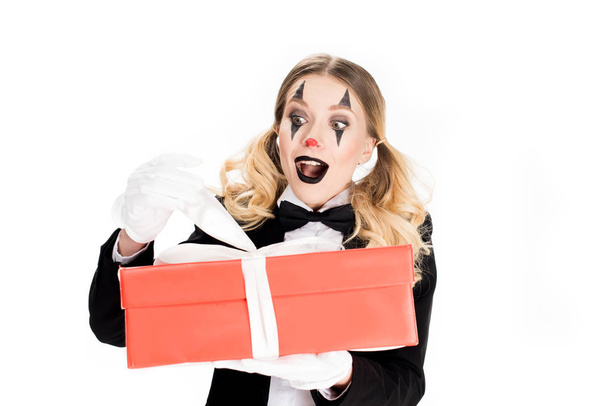 excited female clown holding gift box isolated on white  - Foto, Imagem