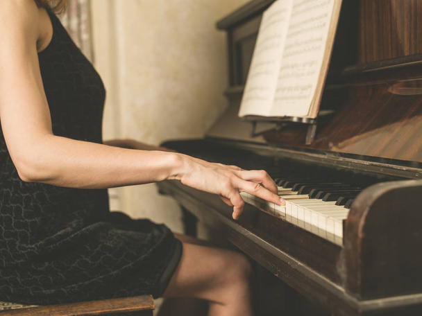 A young woman in a dress is playing the piano - 写真・画像