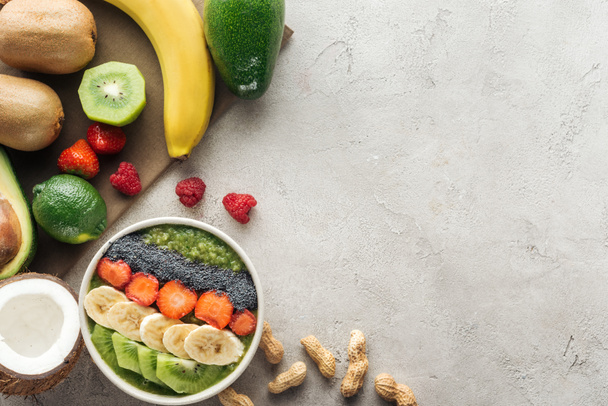 vista superior da tigela de smoothie com frutas frescas e nozes em fundo cinza
 - Foto, Imagem