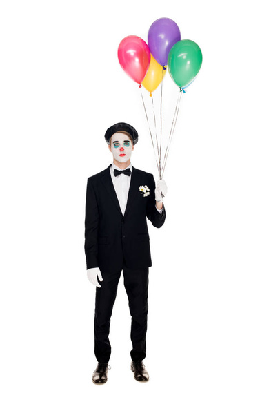 грустный клоун в костюме и черном берете с гелиевыми шариками, изолированными на белом
  - Фото, изображение