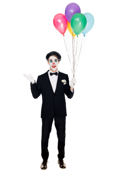 clown souriant en costume et béret noir tenant des ballons d'hélium isolés sur blanc
  - Photo, image