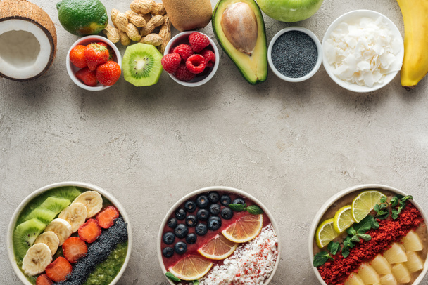 top view of smoothie bowls with ingredients on grey background - Foto, afbeelding