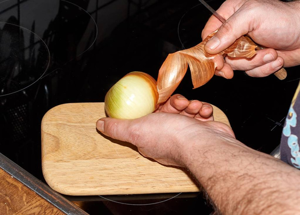 Chef slicing Onion, Allium cepa on the cutting board with a knife. - Photo, Image