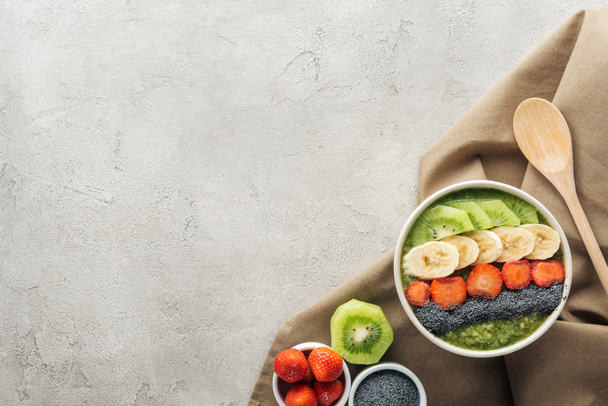 top view of smoothie bowl, wooden spoon and ingredients on grey background with copy space - Photo, Image