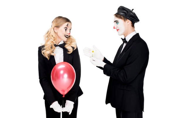 smiling female clown holding balloon and looking at man with flower isolated on white  - Photo, Image