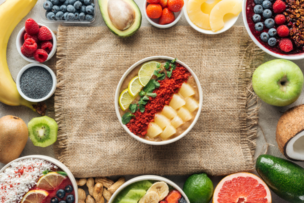 top view of smoothie bowls and frame made of fresh ingredients on sackcloth - Φωτογραφία, εικόνα