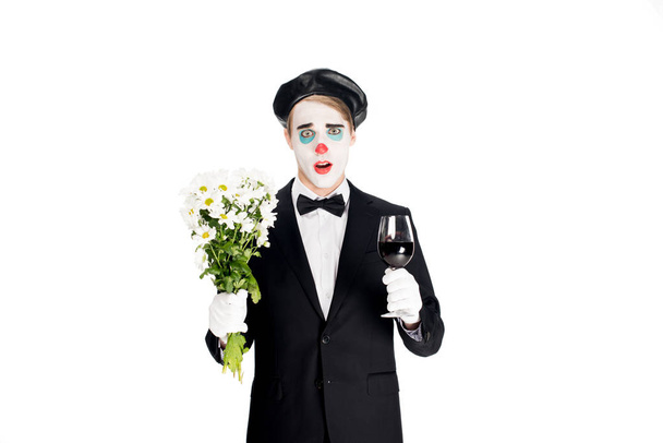 meglepett bohóc gazdaság virágok és a pohár a kezében elszigetelt fehér bor  - Fotó, kép