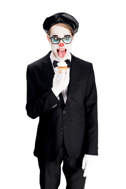 crazy clown in suit showing tongue while eating cupcake isolated on white  - Fotografie, Obrázek