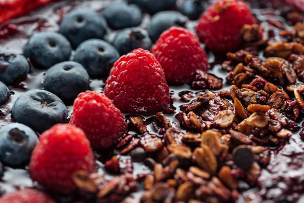 selective focus of blueberries, raspberries and granola in smoothie bowl - Foto, immagini