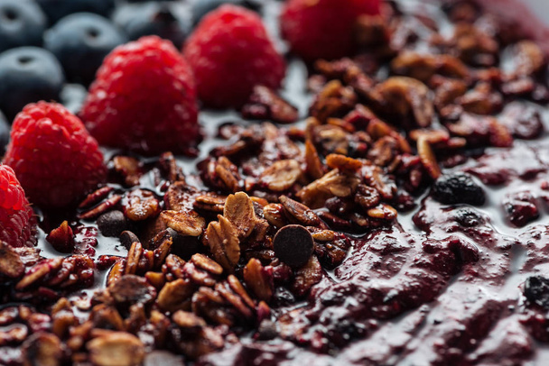 selective focus of blueberries, raspberries and homemade granola in smoothie bowl - Foto, Imagem