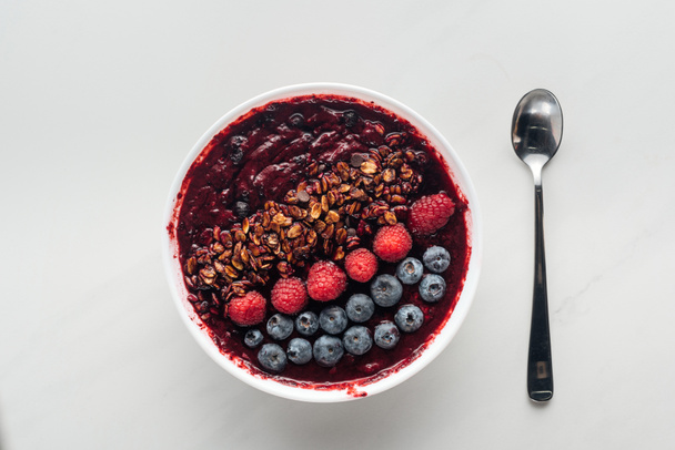 top view of fresh organic smoothie bowl with berries and granola on white background - Foto, immagini