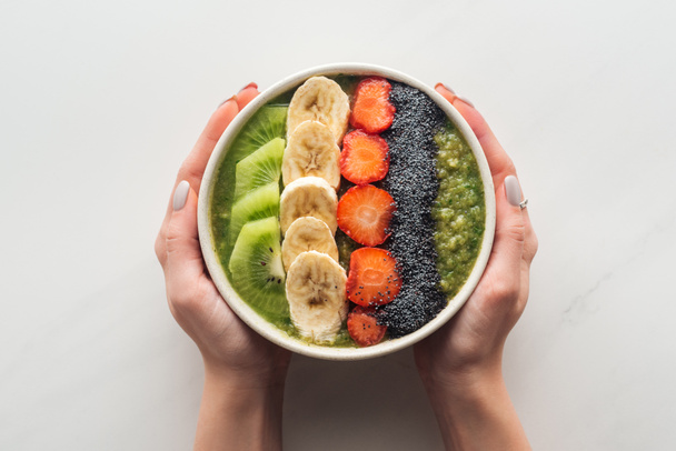cropped view of woman holding smoothie bowl with fresh fruits on white background - Φωτογραφία, εικόνα